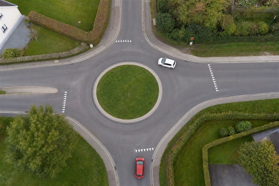 Luchtfoto van een rotonde met vier takken en een bord voorrang verlenen aan elke toegang