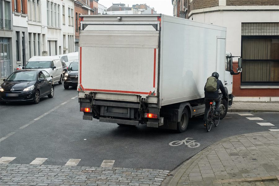 Fietser rechts naast een vrachtwagen die aan een kruispunt rechts wil afslaan