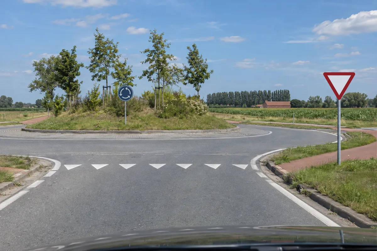 Een rotonde in Vlaanderen met het bord verplicht rondgaand verkeer op het middeneiland en een bord voorrang verlenen aan de toegang.