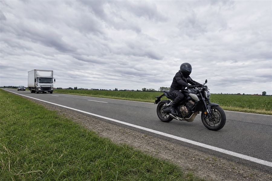 Een motorrijder rijdt voor een vrachtwagen