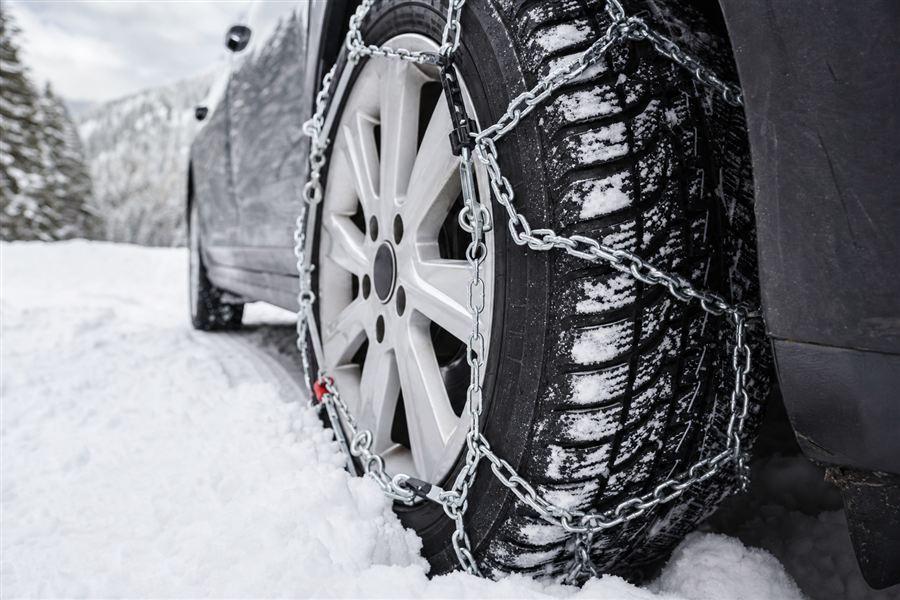 Auto met sneeuwkettingen op een besneeuwde weg