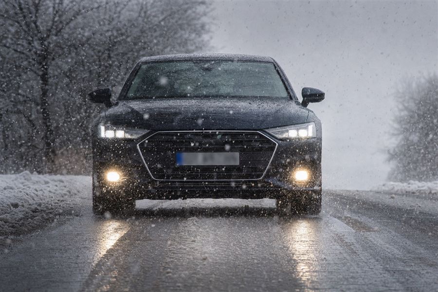 Auto van voren, met lichten aan, in natte sneeuw
