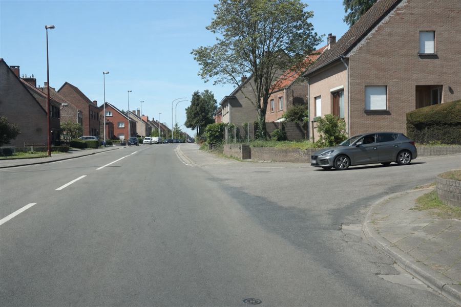 Een voertuig komt uit een straat rechts terwijl een ander op de rijbaan rijdt