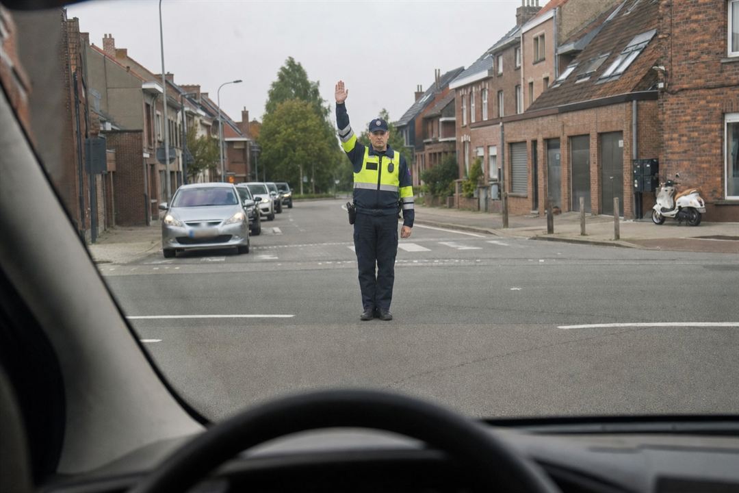 Bevoegd persoon op een kruispunt met één arm recht omhoog, gezien door de voorruit