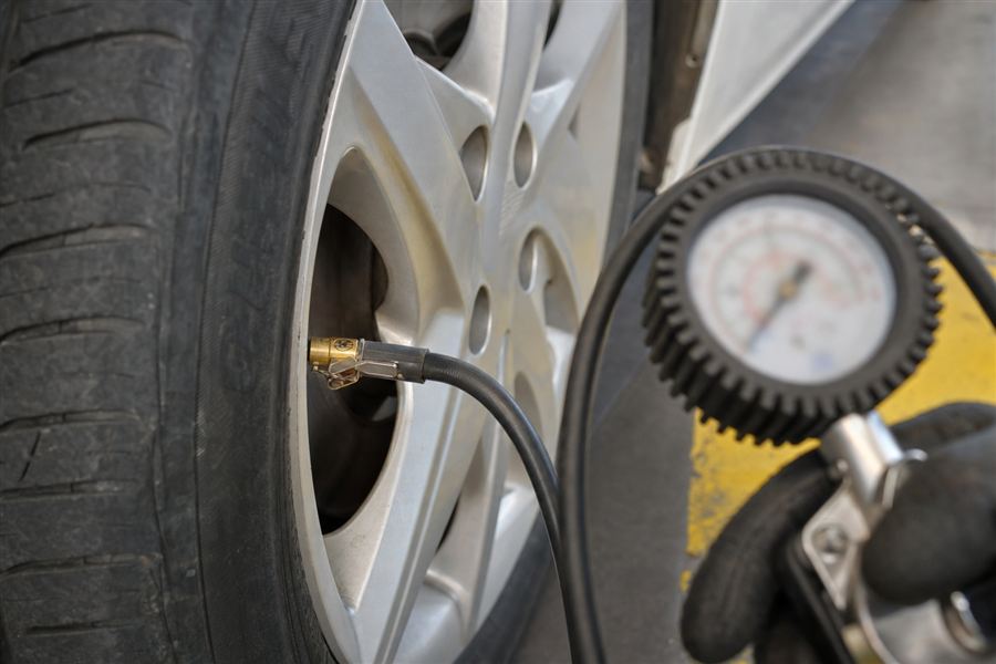 Bestuurder controleert de bandenspanning van zijn auto voor het vertrek