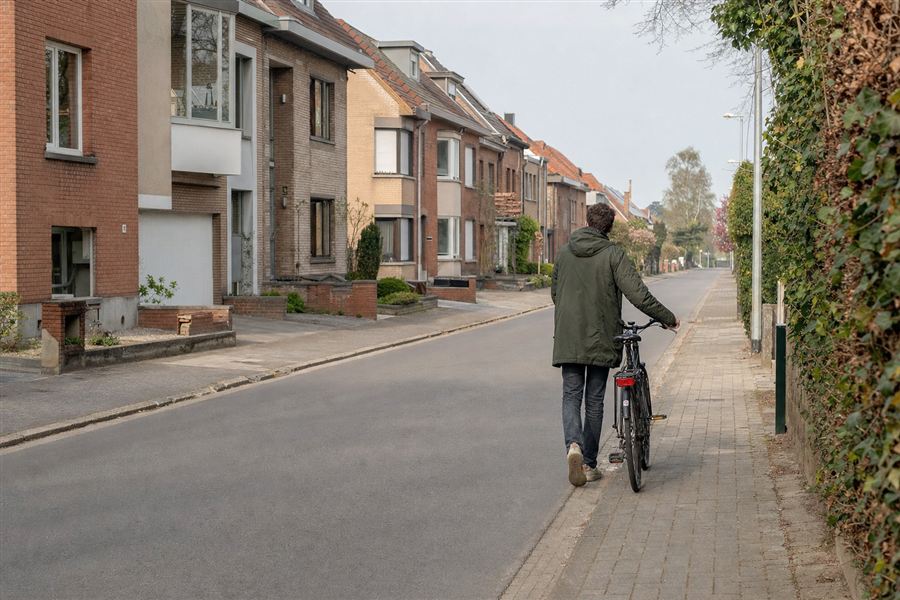 Een persoon leidt zijn fiets aan de hand en loopt ernaast