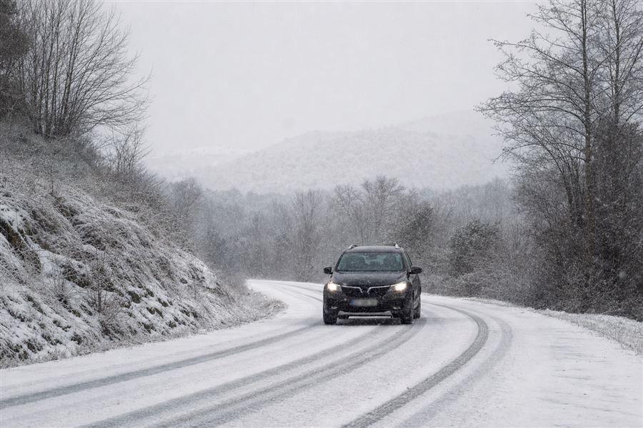 Auto op een besneeuwde weg, met sneeuw die opspat