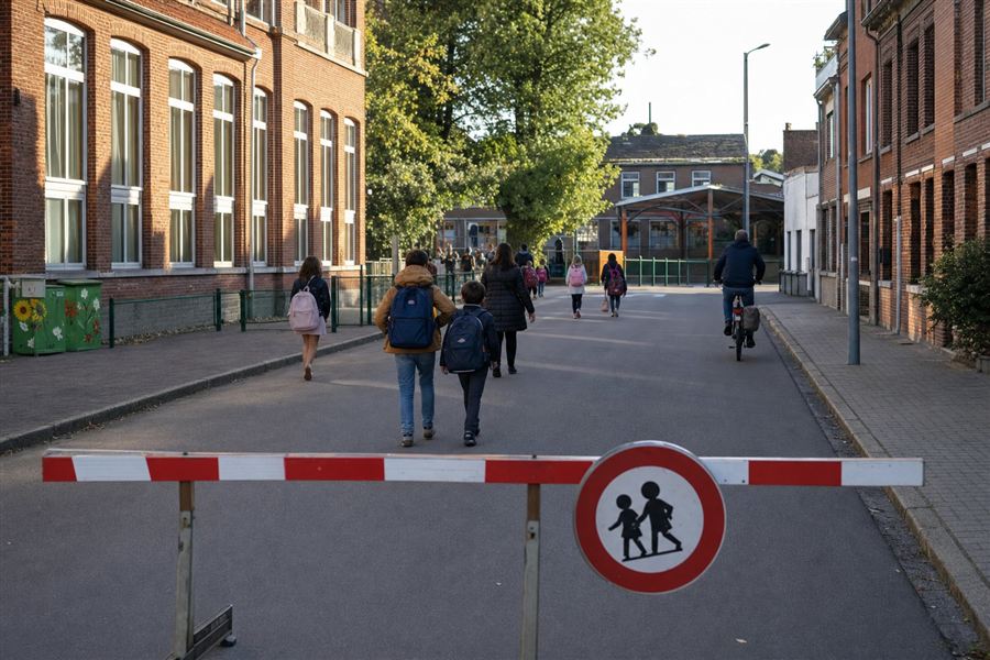 Kinderen te voet en met de fiets voor een school, in een straat zonder auto's