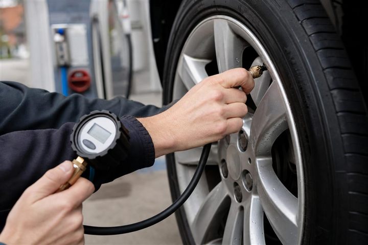 Bestuurder controleert de bandenspanning met een meter aan de bandenpomp